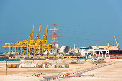 Cranes at construction site against clear blue sky