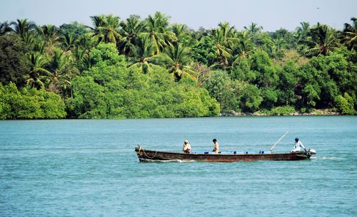 People on boat in sea against sky