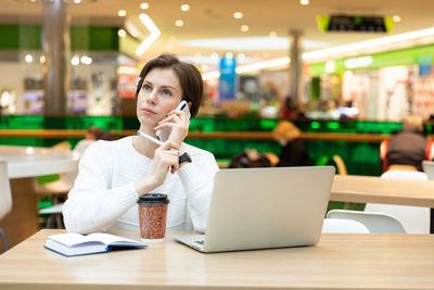 Portrait of young businesswoman using laptop at table