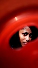 Close-up portrait of teenage girl seen through red plastic