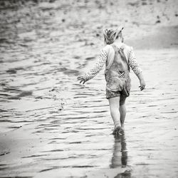 Rear view of girl walking on shore at beach