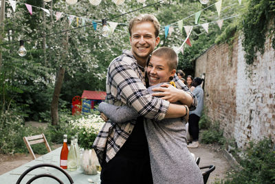 Side view of male and female friends embracing each other at dinner party in back yard