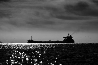 Silhouette lighthouse by sea against sky