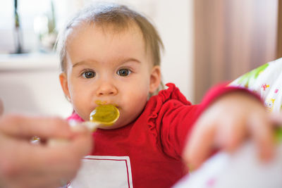 Feeding 1 year old baby with spoon, solid food. newborn feeding concept