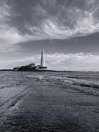 Lighthouse by sea against sky