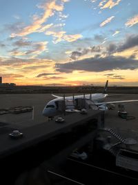 Airplane on runway against sky during sunset