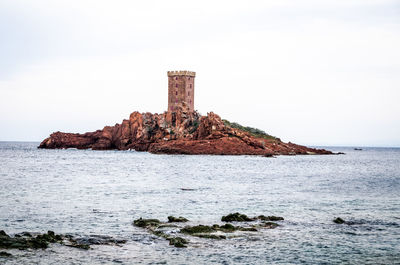 Built structure on rock by sea against clear sky