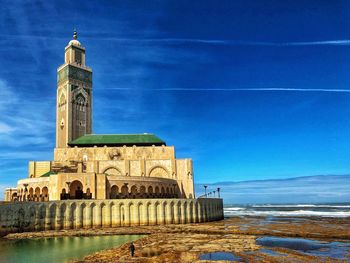 View of building by sea against blue sky