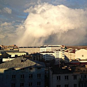 Buildings in city against cloudy sky