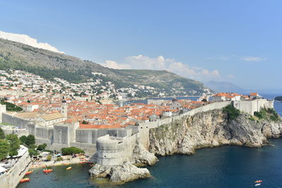 Aerial view of town by sea against sky