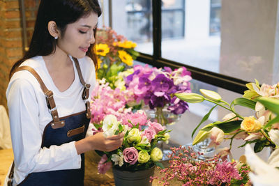 Smiling young woman holding bouquet in store