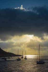 Sailboats sailing on sea against sky during sunset