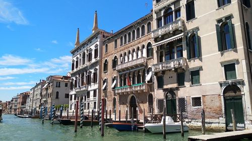 Buildings by canal against sky in city