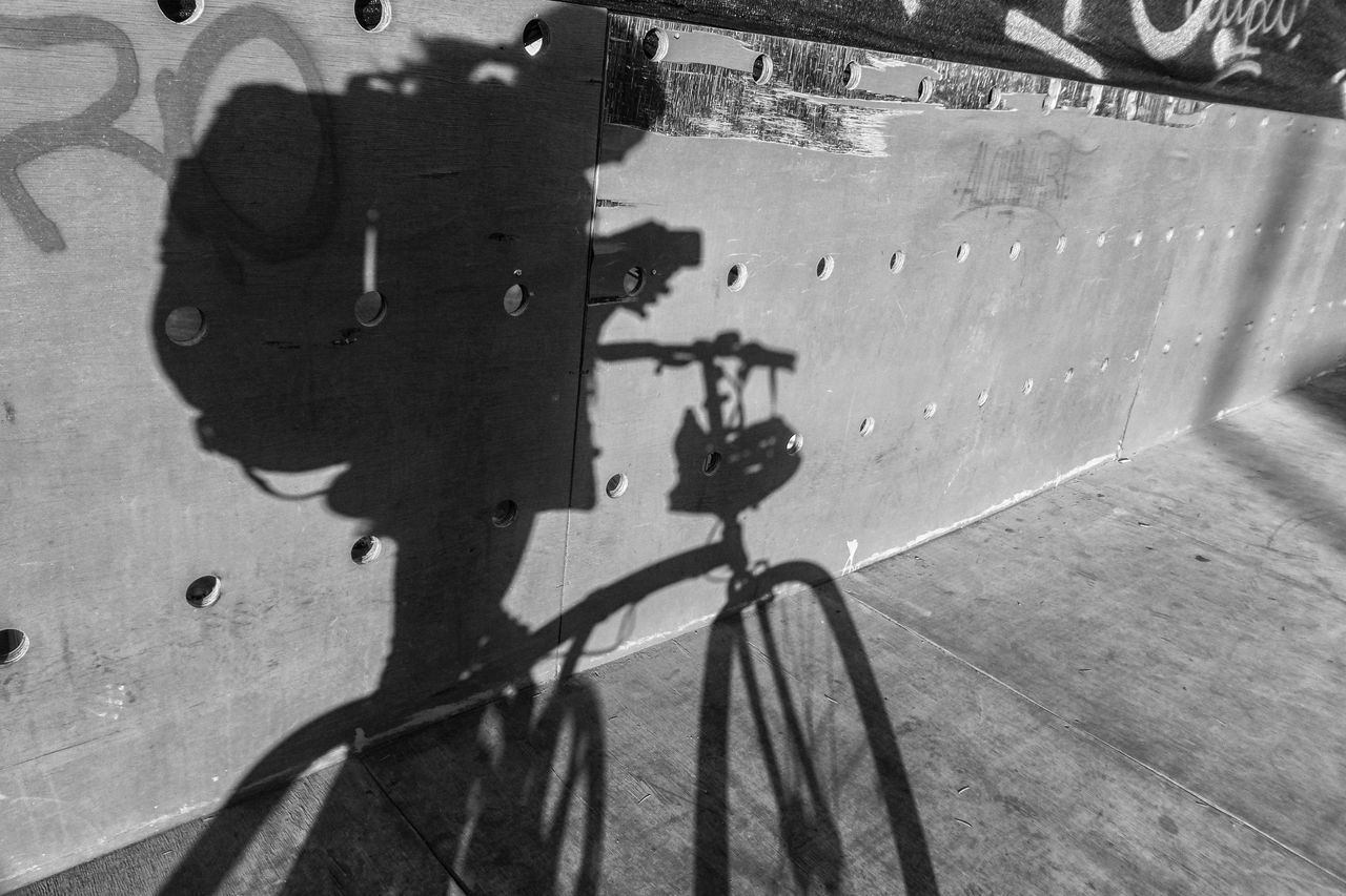 HIGH ANGLE VIEW OF SHADOW ON BICYCLE WALL