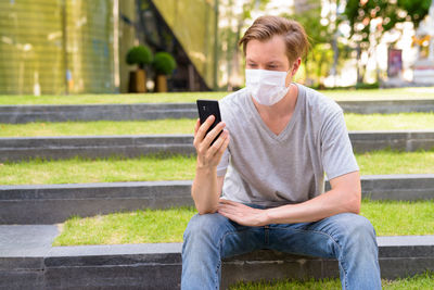 Young man using mobile phone while sitting on bench