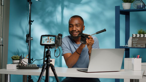 Young man vlogging on camera at desk