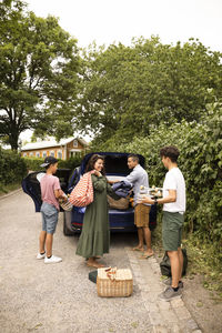 Family helping each other while loading picnic supplies in car trunk