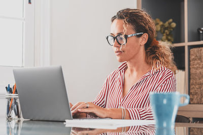 Woman using mobile phone while sitting on table