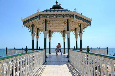 Tourists on top of building against blue sky