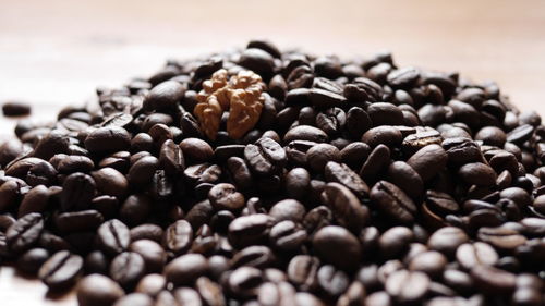 Close-up of roasted coffee beans and walnut on table