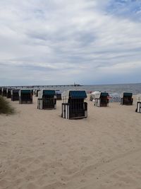 Hooded chairs on beach against sky