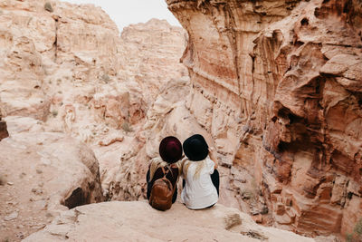 Rear view of friends sitting on rock formation