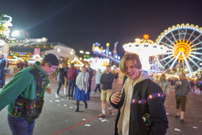 Drunk men standing at amusement park during night