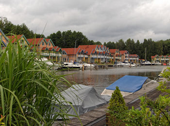 Houses by lake and buildings against sky