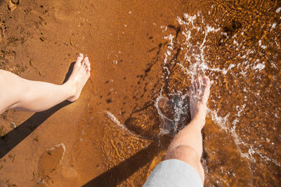 Low section of man on sand at beach