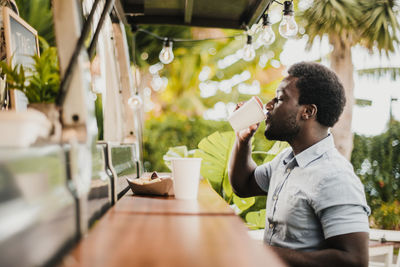 Side view of man drinking coffee at food truck counter