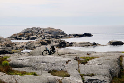 Scenic view of rocks by sea against sky