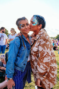 Portrait of smiling young woman being kissed by friend at party