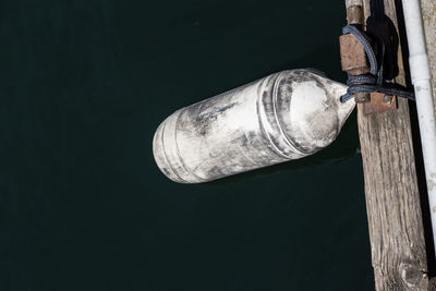 Low section of person sitting on wooden pole against black background