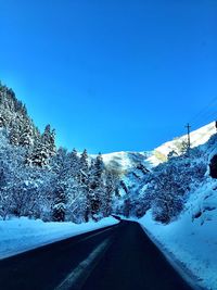 Scenic view of snow covered mountain against blue sky