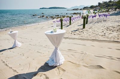 Chairs on beach by sea against sky