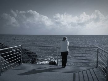 Pier on sea against cloudy sky