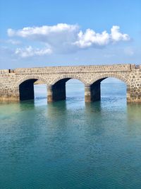 Arch bridge over river against sky