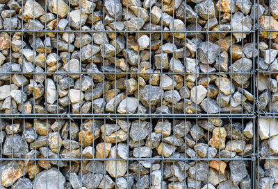 Full frame shot of stones stacked by metallic fence