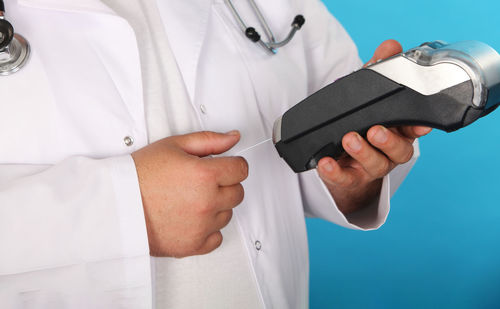 Midsection of doctor holding credit card reader