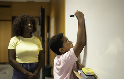 Side view of woman with arms raised against wall