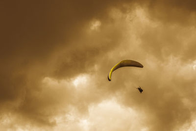 Low angle view of silhouette people flying against sky