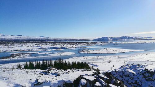 Scenic view of frozen lake against clear blue sky