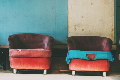 Old empty sofa against wooden wall