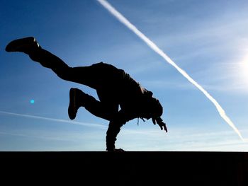 Low angle view of silhouette people against blue sky