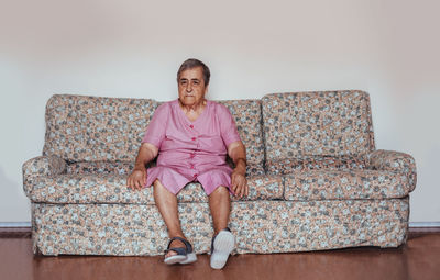 Front view of a senior woman with alzheimer's mental health issues sitting in a sofa alone in her home