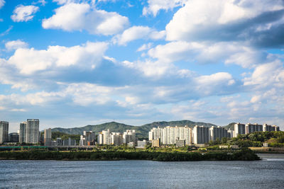 Buildings by sea against sky in city