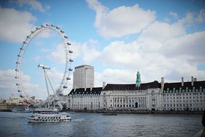 View of ferris wheel in city against cloudy sky