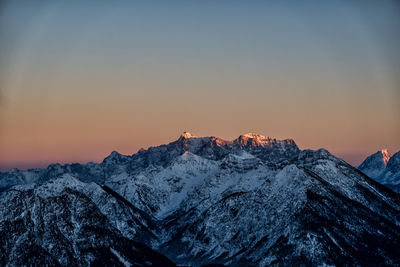 Scenic view of snowcapped mountains against clear sky during sunset