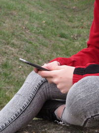 Low section of man using mobile phone in grass