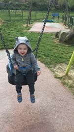 Full length of happy baby boy enjoying on swing at park